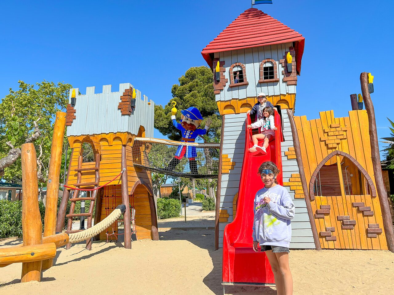 Castle-themed playground with slide and happy children at CAPFUN Alba campsite in CREIXELL (43).