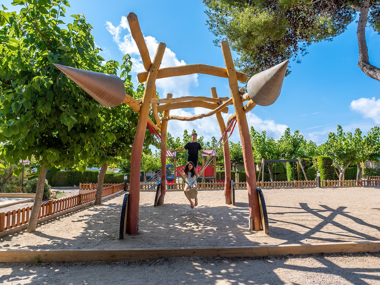 Playground with swings and children, at CAPFUN Alba campsite in CREIXELL (43).