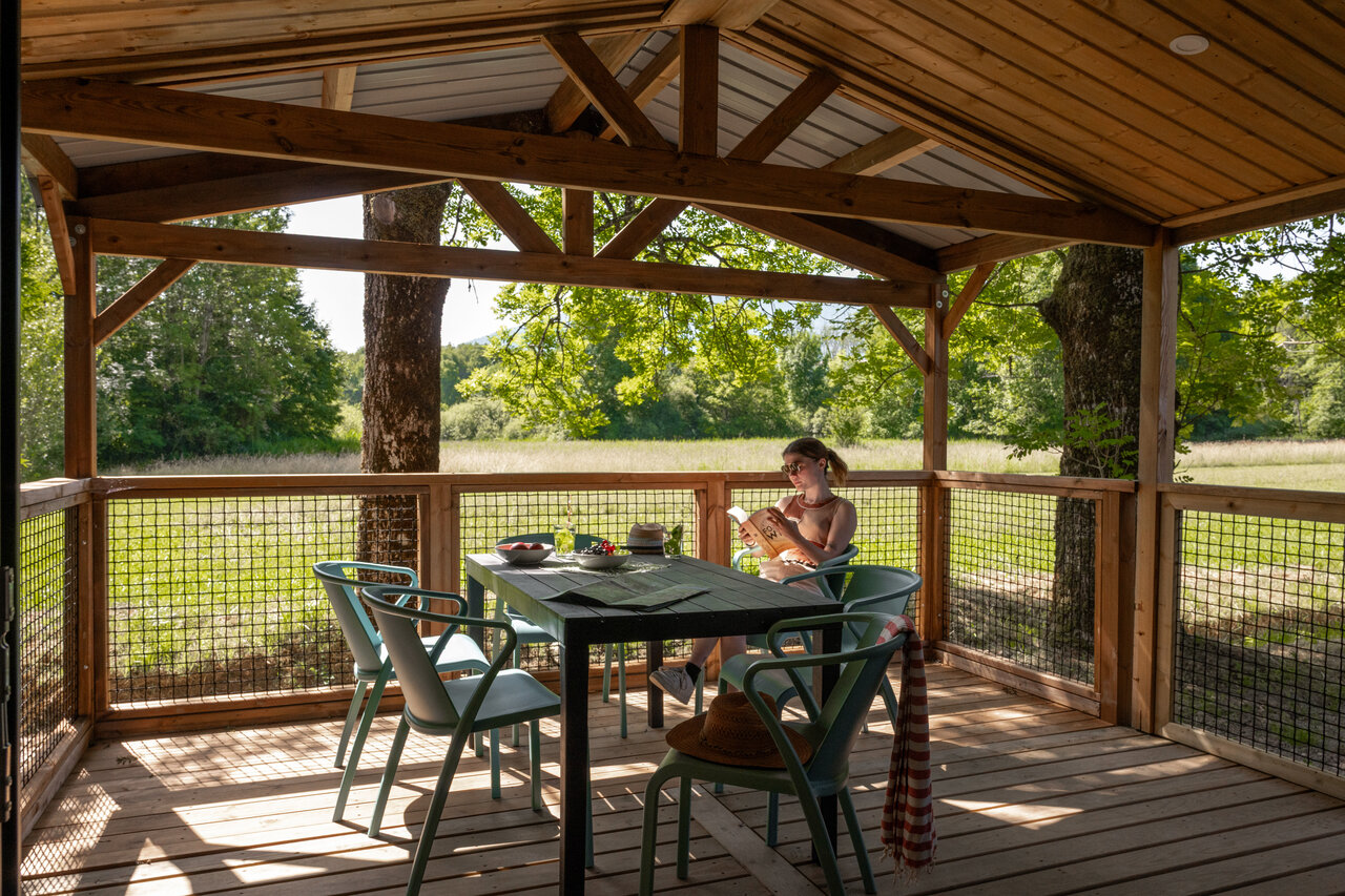 Accommodation terrace, woman reading, nature CLICOCHIC Aloua campsite Sevrier (74).