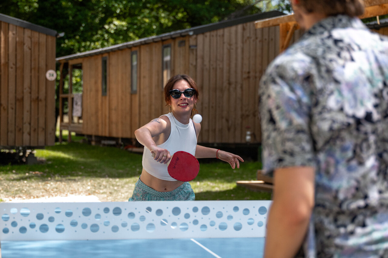Smiling woman playing table tennis near accommodations at CLICOCHIC Aloua campsite in Sevrier (74).
