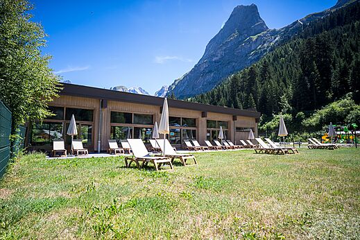 Modern building, chairs and mountain view at CLICOCHIC Alpes Lodges campsite.