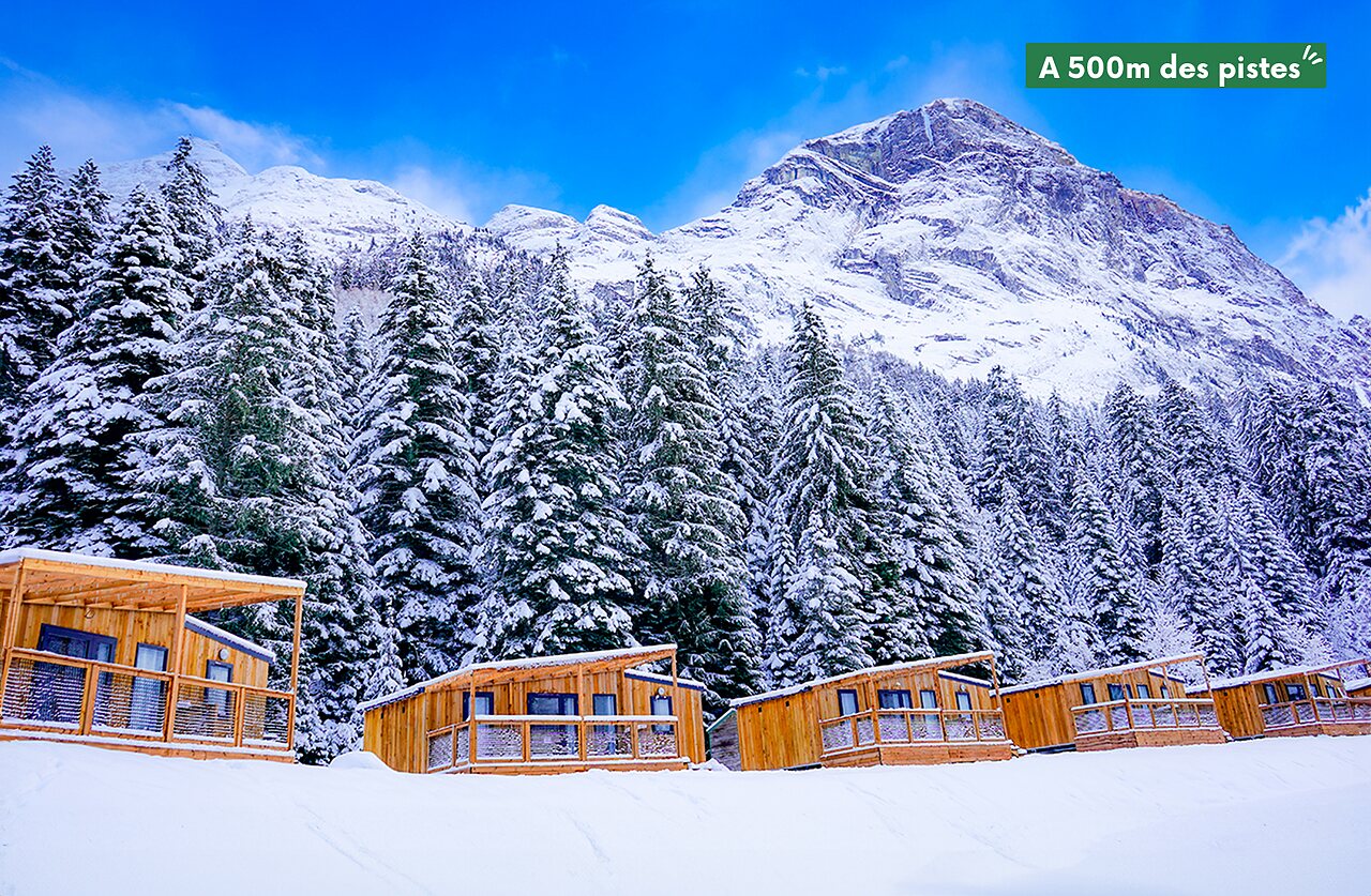 Snow-covered wooden Mobile homes, mountains and forest at CLICOCHIC Alpes Lodges Pralognan la Vanoise.