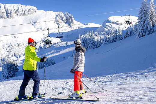 Skiers on snowy slope, chairlift, mountains at CLICOCHIC Alpes Lodges campsite.