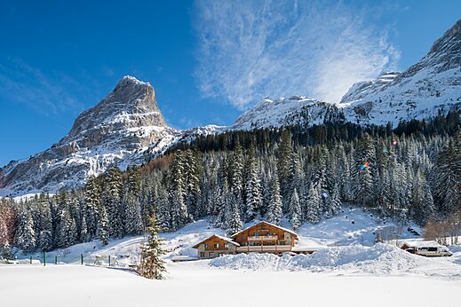 Snowy mountains, wooden accommodations at CLICOCHIC Alpes Lodges campsite in Pralognan la Vanoise.