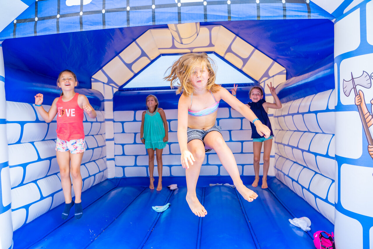 Children jumping in blue and white inflatable castle at CAPFUN Armor H�ol campsite in Piriac sur Mer (44).