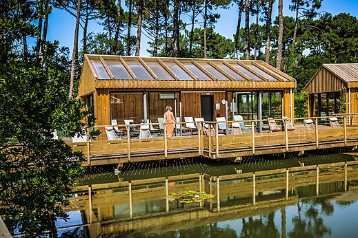 Wooden spa building with deck over water at LIBRANOO Naturiste Arnaoutchot campsite in Veille-Saint-Girons, Landes, France.