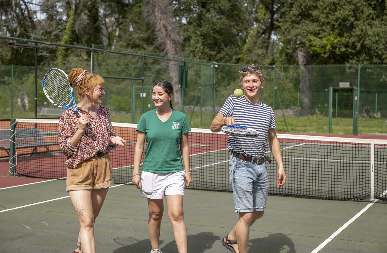 Young people playing tennis on the court at CLICOCHIC Art de Vivre campsite in Ch�teauneuf du Pape.