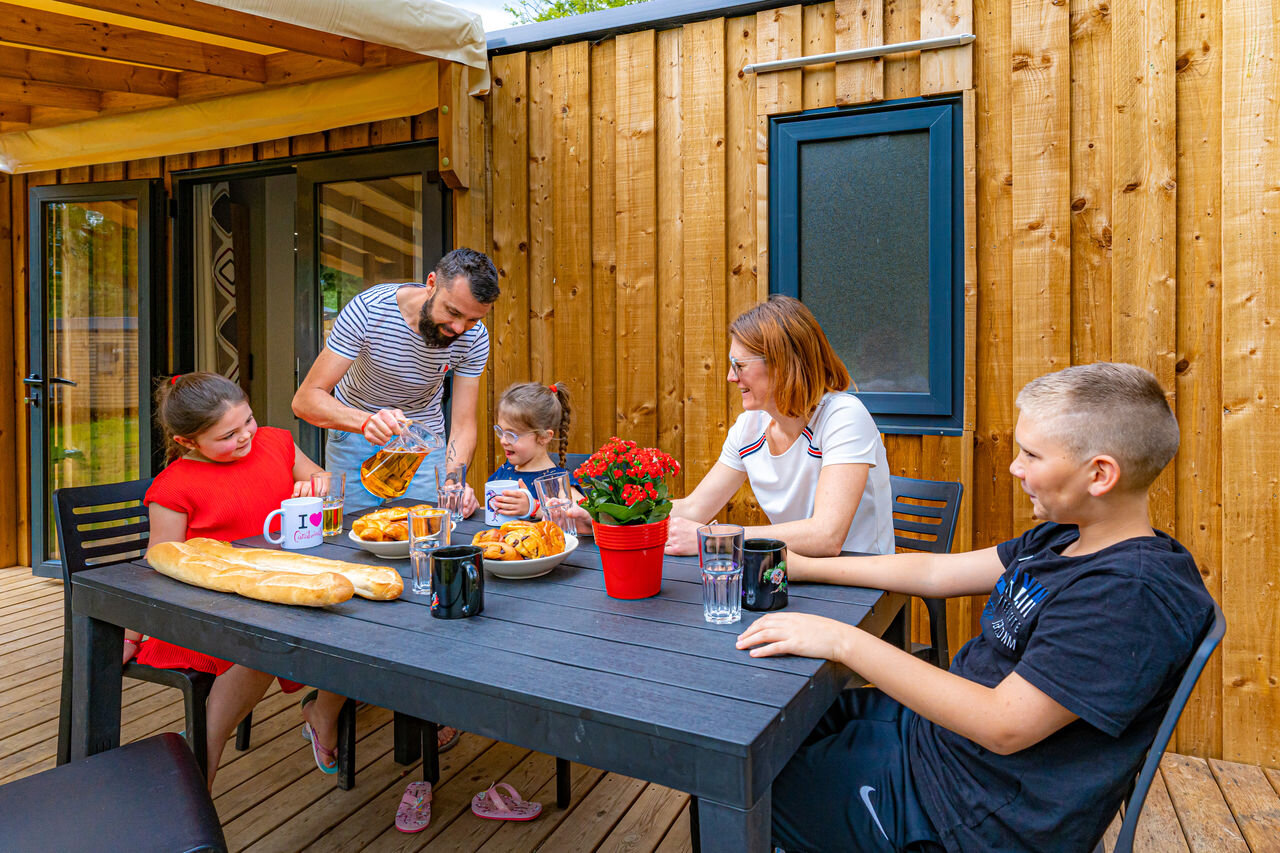 Family having breakfast on a mobile home terrace, at CAPFUN Aube campsite in Deltebre, Tarragona.