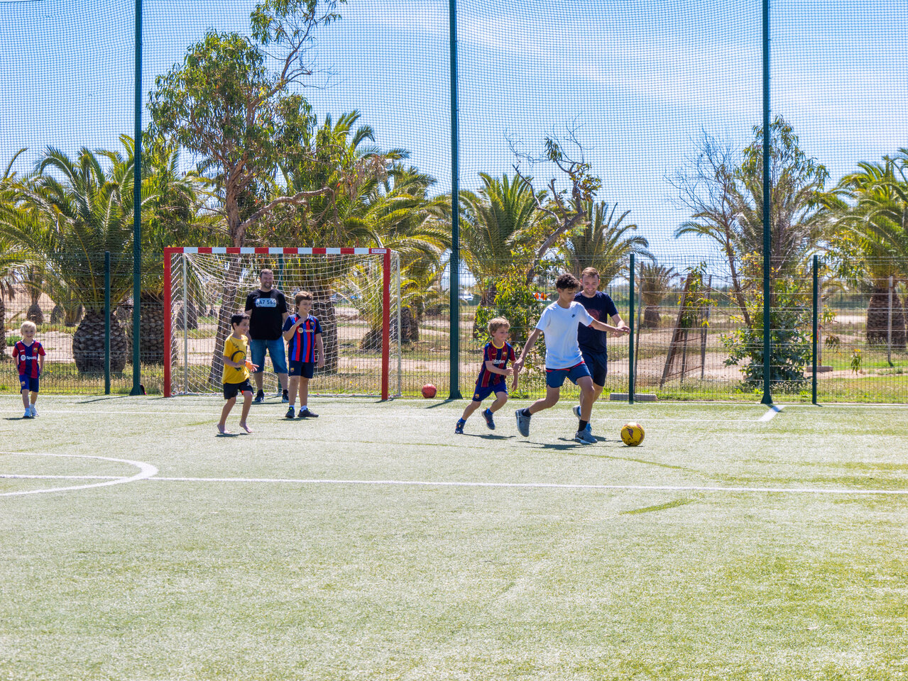 Children playing football on multisport pitch at CAPFUN Aube campsite in Deltebre, Tarragona.