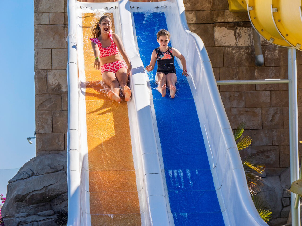 Two happy girls on a water slide at CAPFUN Aube campsite in Deltebre, Tarragona.