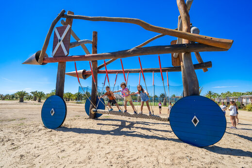 Unique wooden playground with children on rope bridge at CAPFUN Aube campsite in Deltebre, Tarragona.