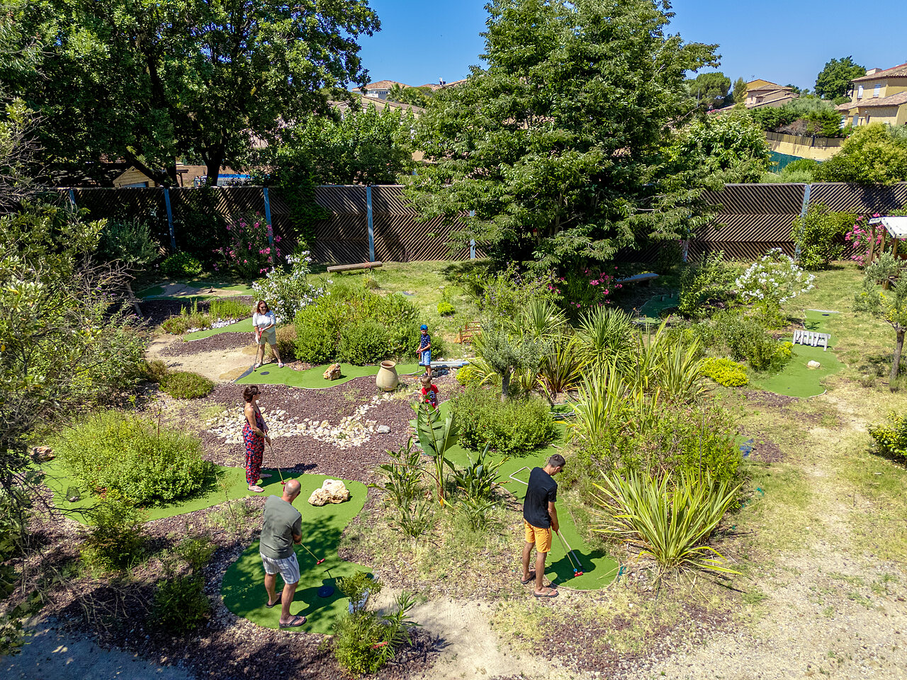 Landscaped mini-golf course with families playing at CAPFUN Aubr�des campsite in Puget sur Argens (83).