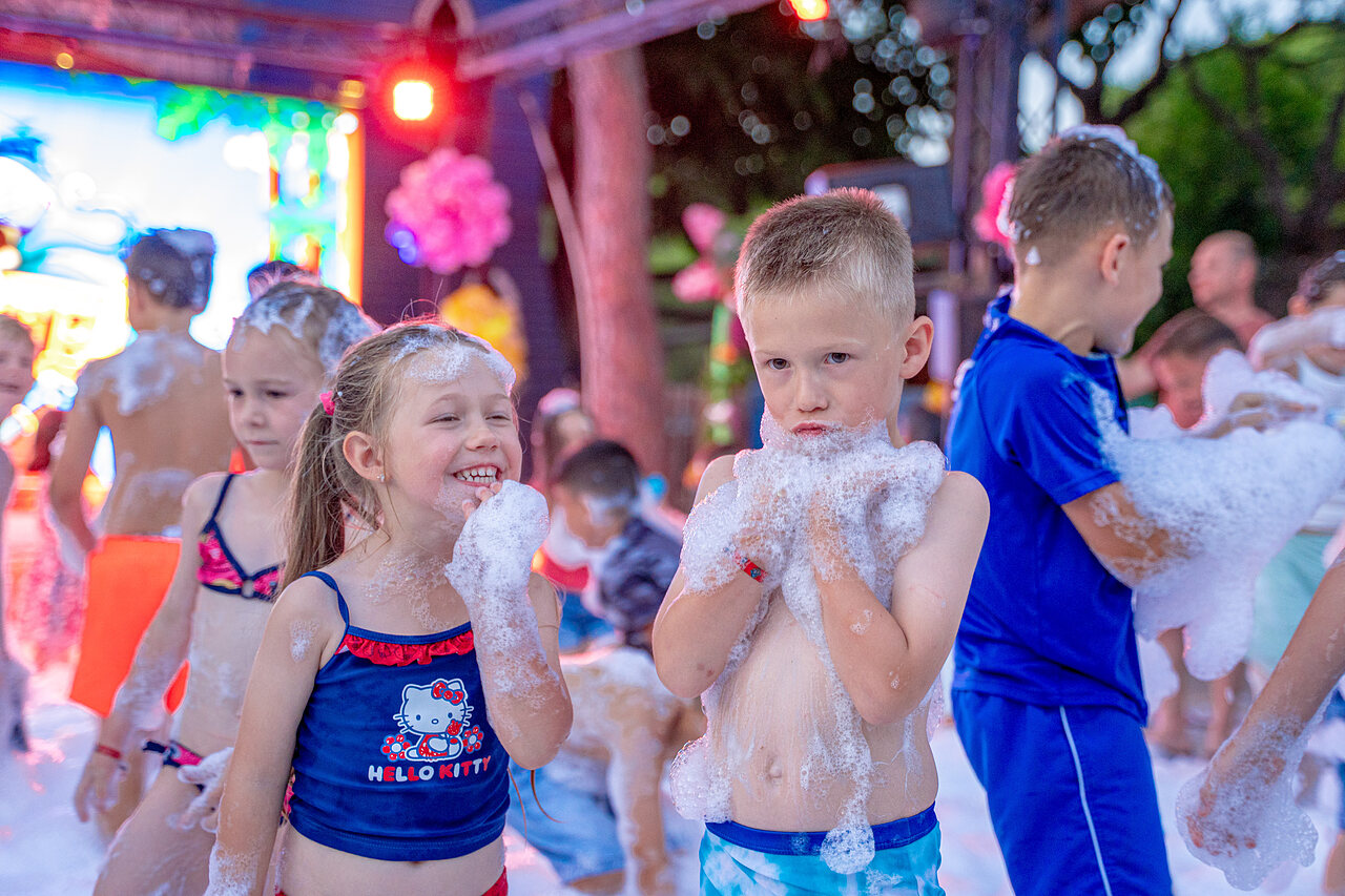 Happy children playing in foam during an animation party at CAPFUN Aubr�des campsite in Puget sur Argens (83).