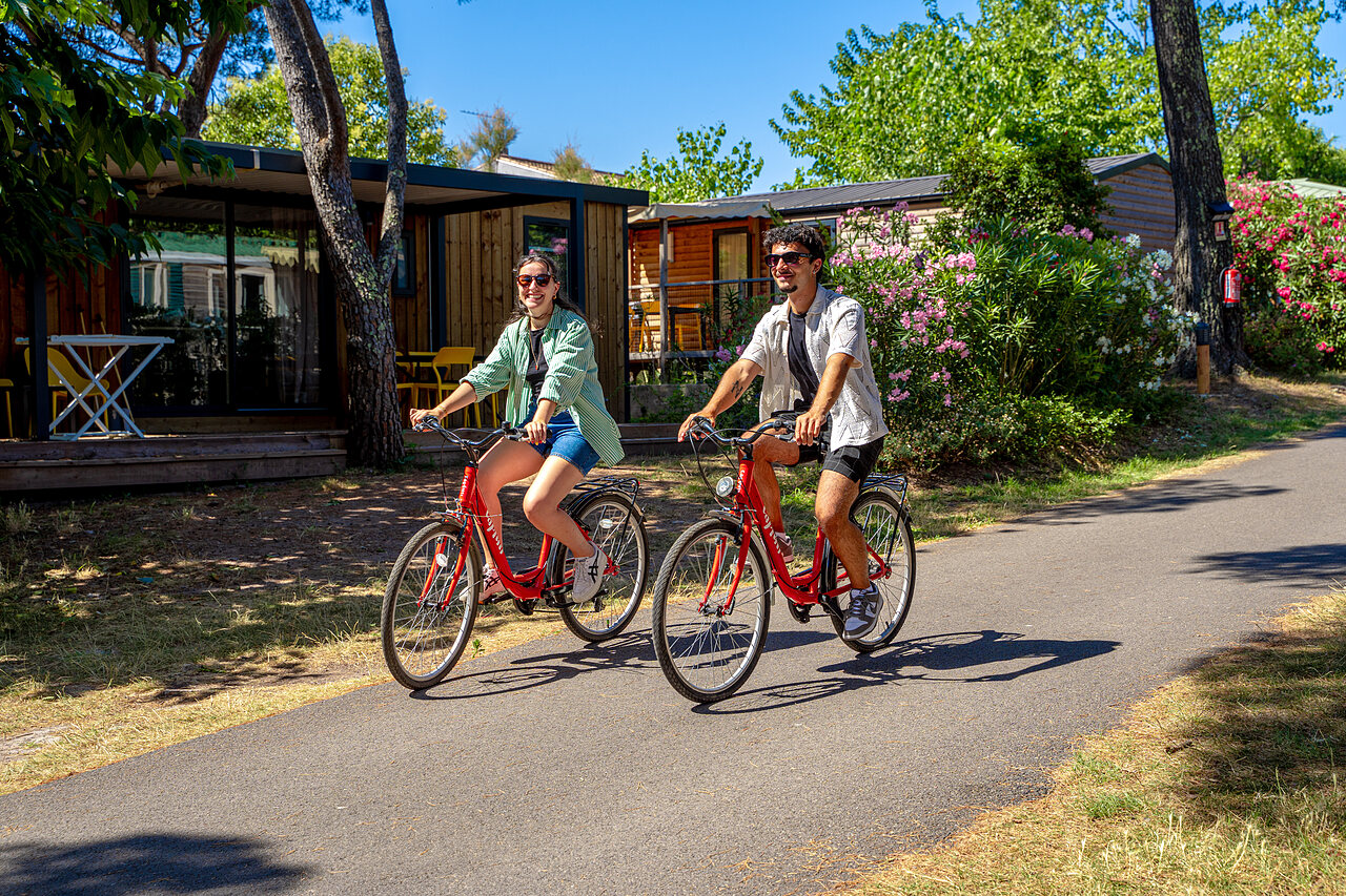 Smiling couple cycling, mobile homes at CAPFUN Aubr�des campsite in Puget sur Argens.