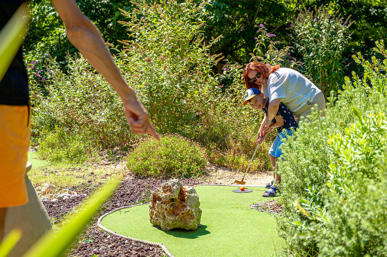 Child and adult playing mini-golf on a green course at CAPFUN Aubr�des campsite in Puget sur Argens (83).