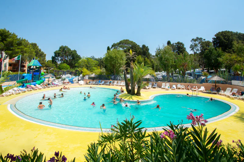 Outdoor pool, slide and palm trees at CLICOCHIC campsite in Cavalaire-sur-Mer.