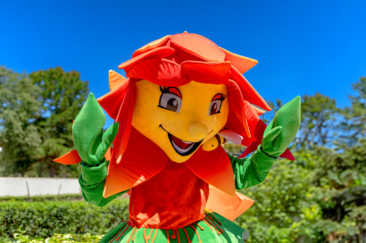 Smiling flower mascot with a bee for entertainment at CLICOCHIC Baie de Cavalaire campsite.