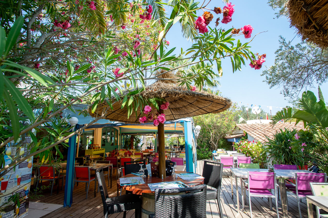 Outdoor restaurant-bar and flowery terrace at CLICOCHIC Baie de Cavalaire campsite in Cavalaire-sur-Mer.