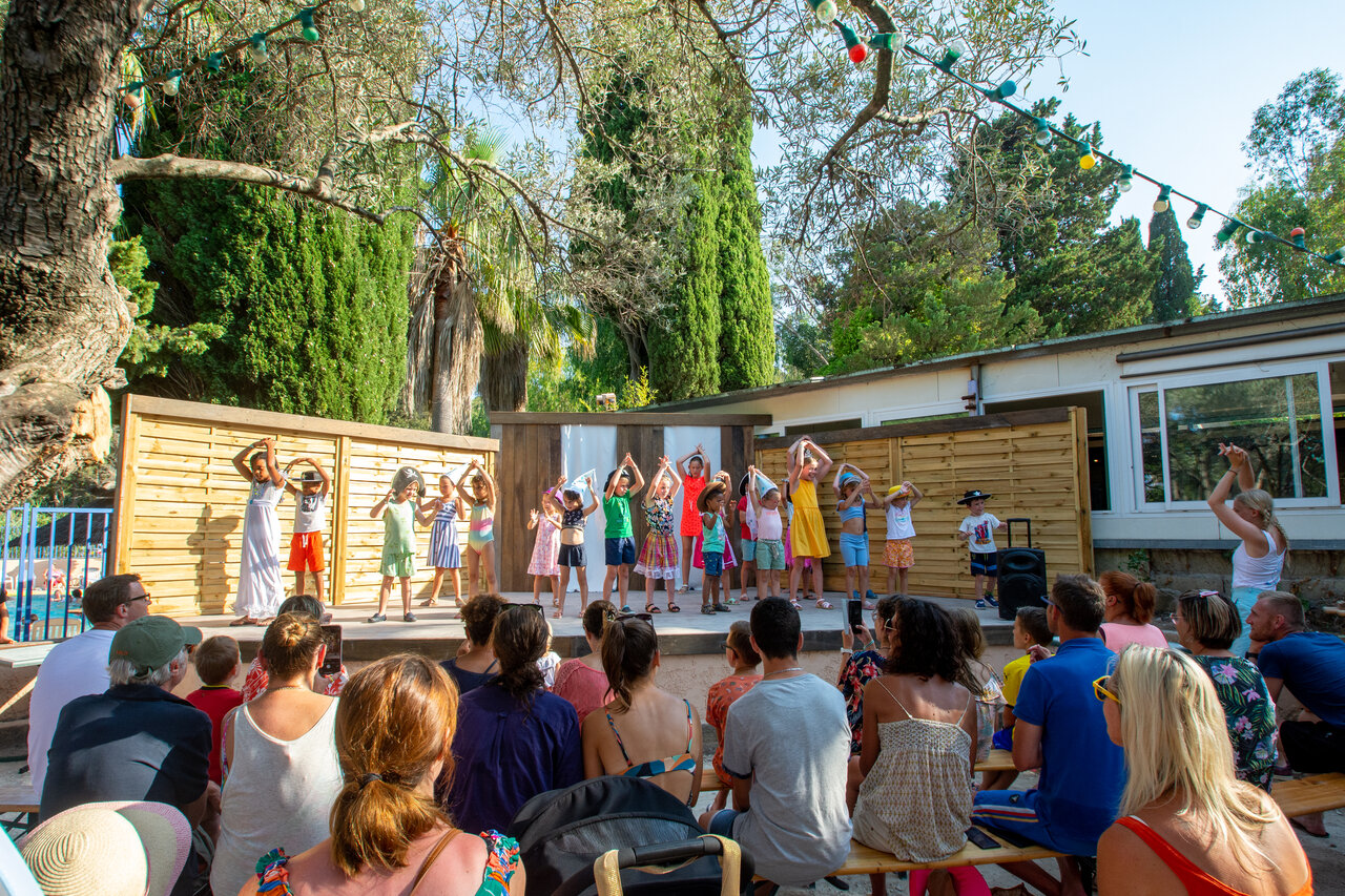 Children's entertainment on stage, audience at CLICOCHIC Baie de Cavalaire campsite.