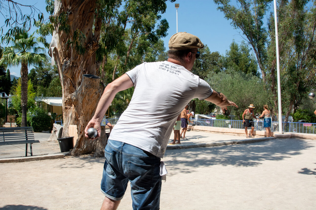 Man playing p�tanque on a shaded court at CLICOCHIC Baie de Cavalaire campsite in Cavalaire-sur-Mer (83).