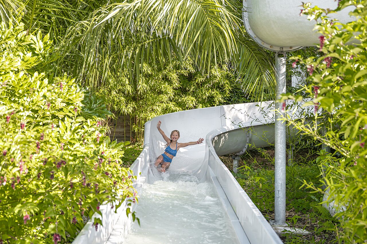Smiling child on water slide at CLICOCHIC Baie de Douarnenez campsite in Poullan-sur-Mer.