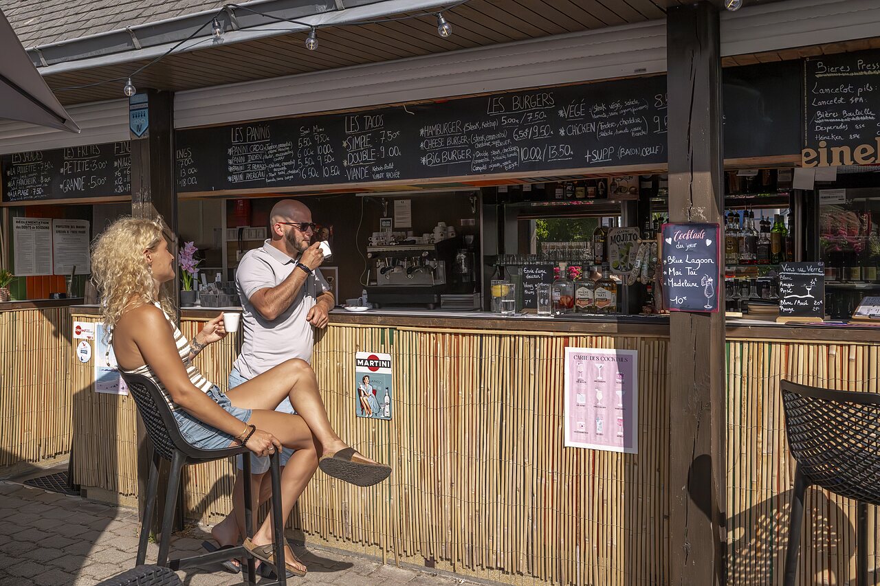 Bar-restaurant with terrace, guests enjoying drinks and meals at CLICOCHIC Baie de Douarnenez campsite.