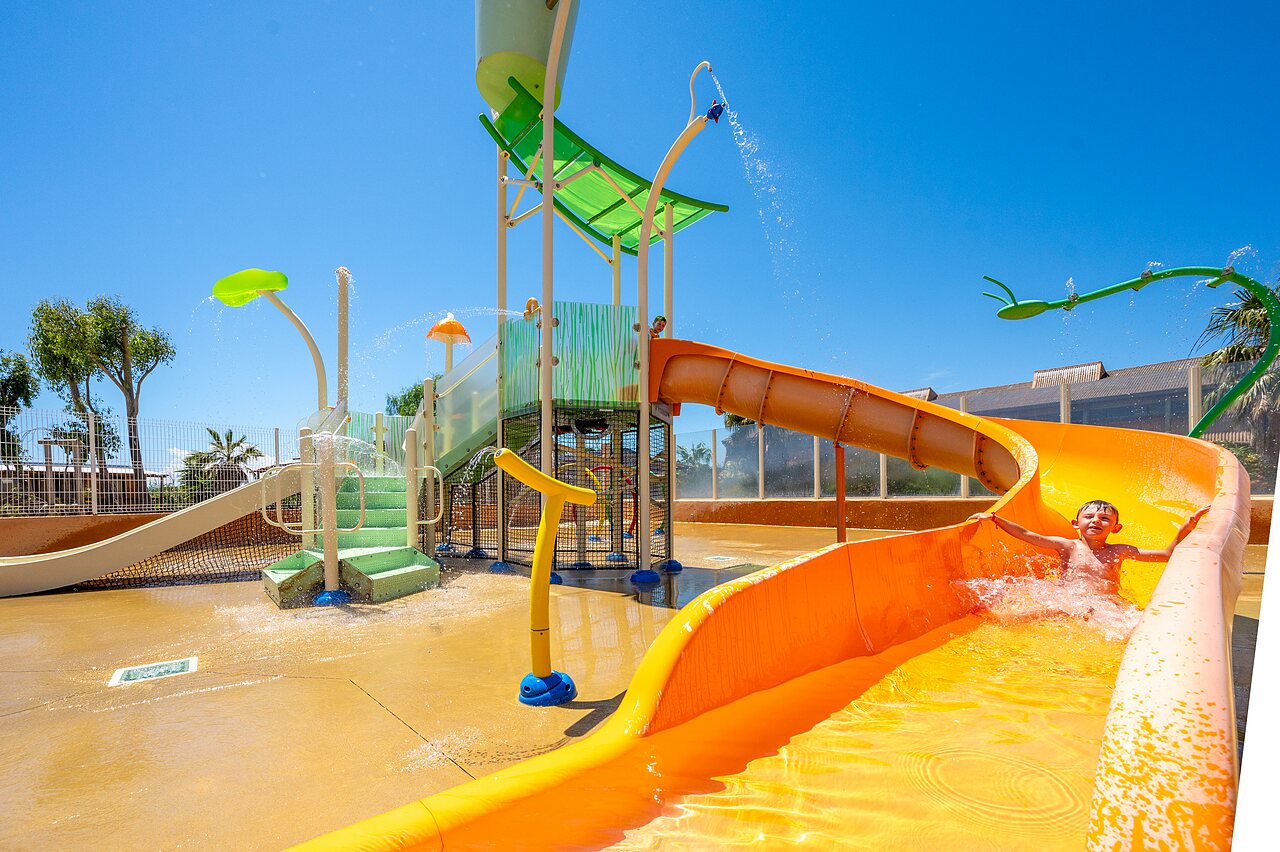 Child on orange water slide, water games at CAPFUN Barbacane campsite in NARBONNE (11).
