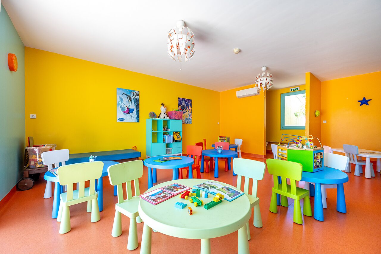 Colorful kids' club with tables, chairs, games at CAPFUN Barbacane NARBONNE (11).