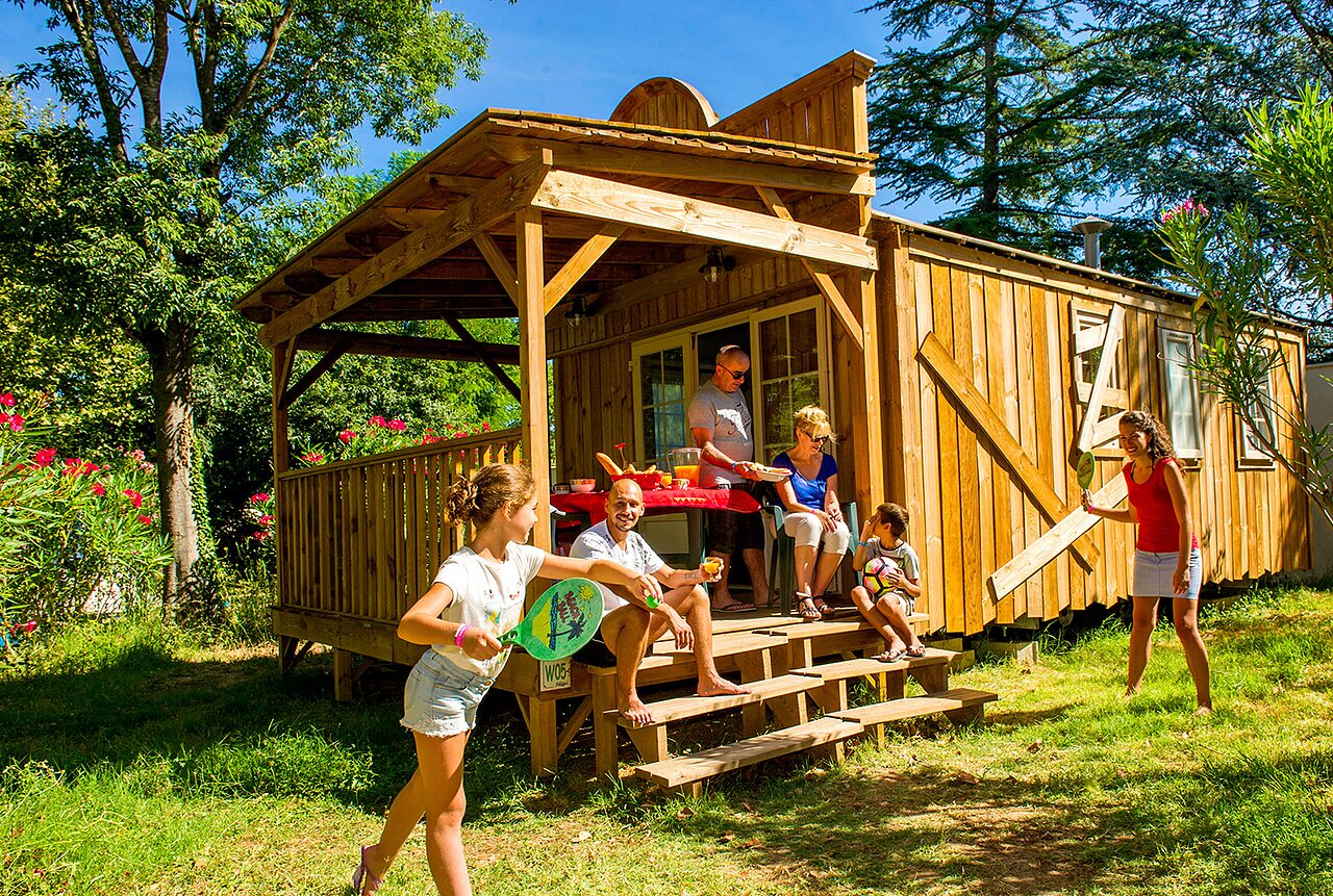 Family enjoying a wooden cabin and playing at CAPFUN Bastide campsite in N�mes (30).