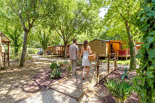 Couple walking towards shaded Mobile-homes at CAPFUN Bastide campsite in N�mes (30).