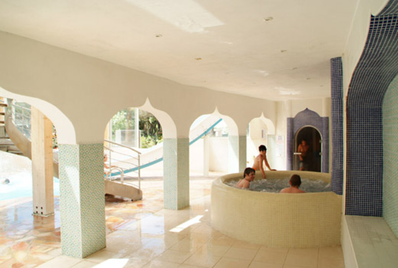 Indoor jacuzzi and water slide at CAPFUN La Baume - La Palmeraie campsite.