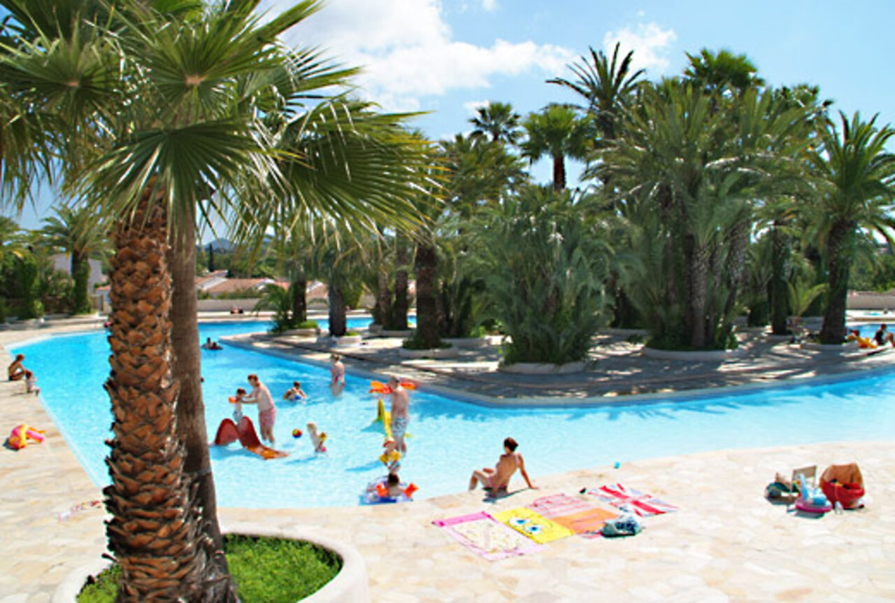Large outdoor swimming pool with palm trees and water games at CAPFUN La Baume - La Palmeraie campsite in Fr�jus (83).
