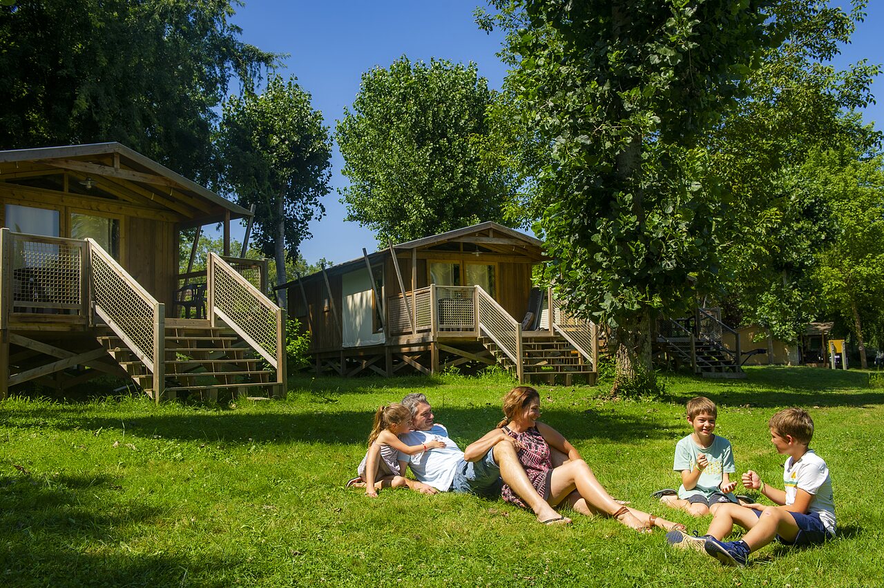 Family relaxing in front of Mobile-homes at CLICOCHIC Beau Rivage campsite in LA ROQUE-GAGEAC.