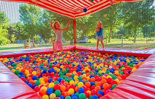 Happy children playing in a large colorful ball pit at camping CLICOCHIC Beau Rivage in LA ROQUE-GAGEAC.