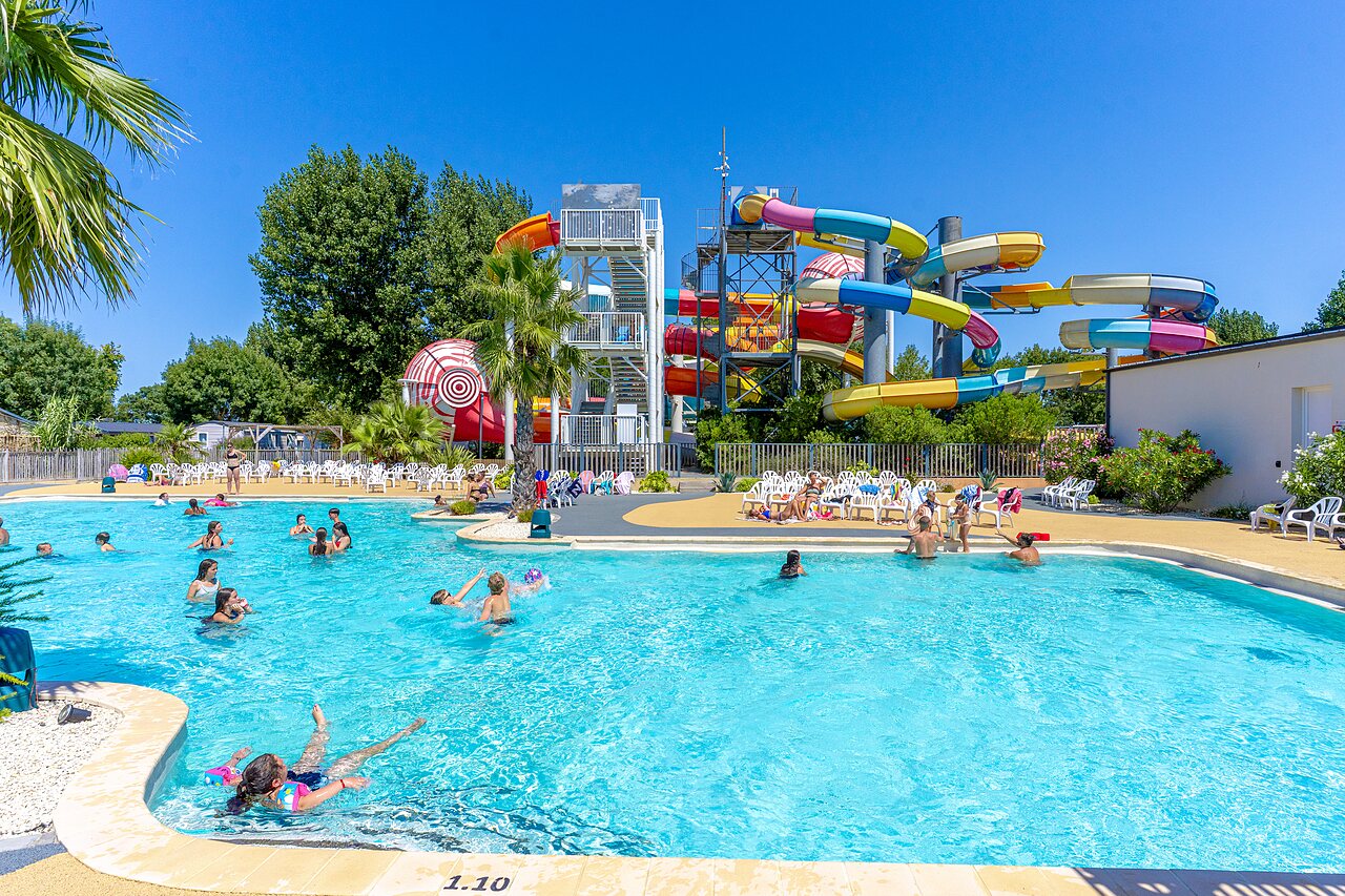 Outdoor swimming pool with colorful water slides and swimmers at CAPFUN Bel Air in Aiguillon sur Mer (85).