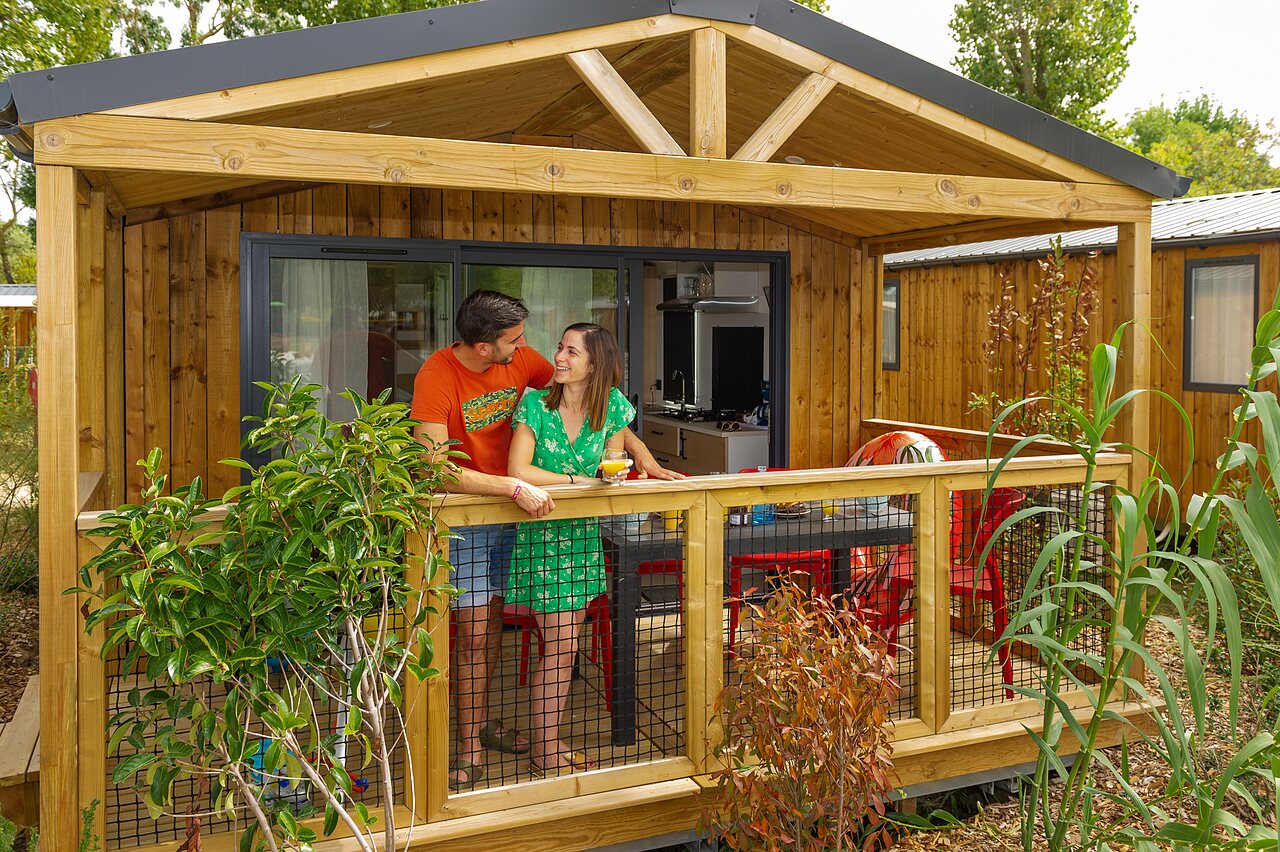 Couple on modern mobile home terrace at CAPFUN Bel Air campsite in Aiguillon sur Mer (85).