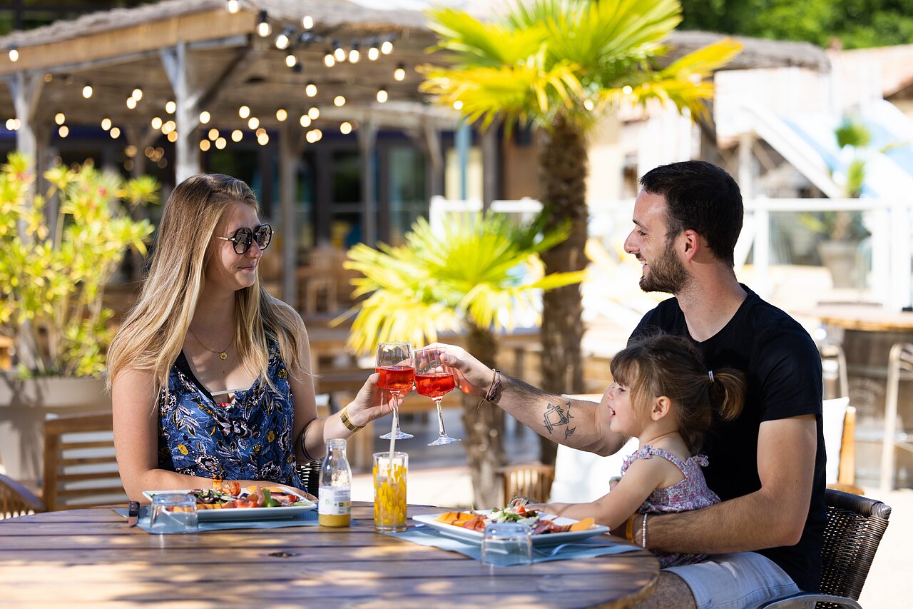 Happy family dining on the restaurant terrace at CLICOCHIC Bimbo campsite in BISCARROSSE (40).