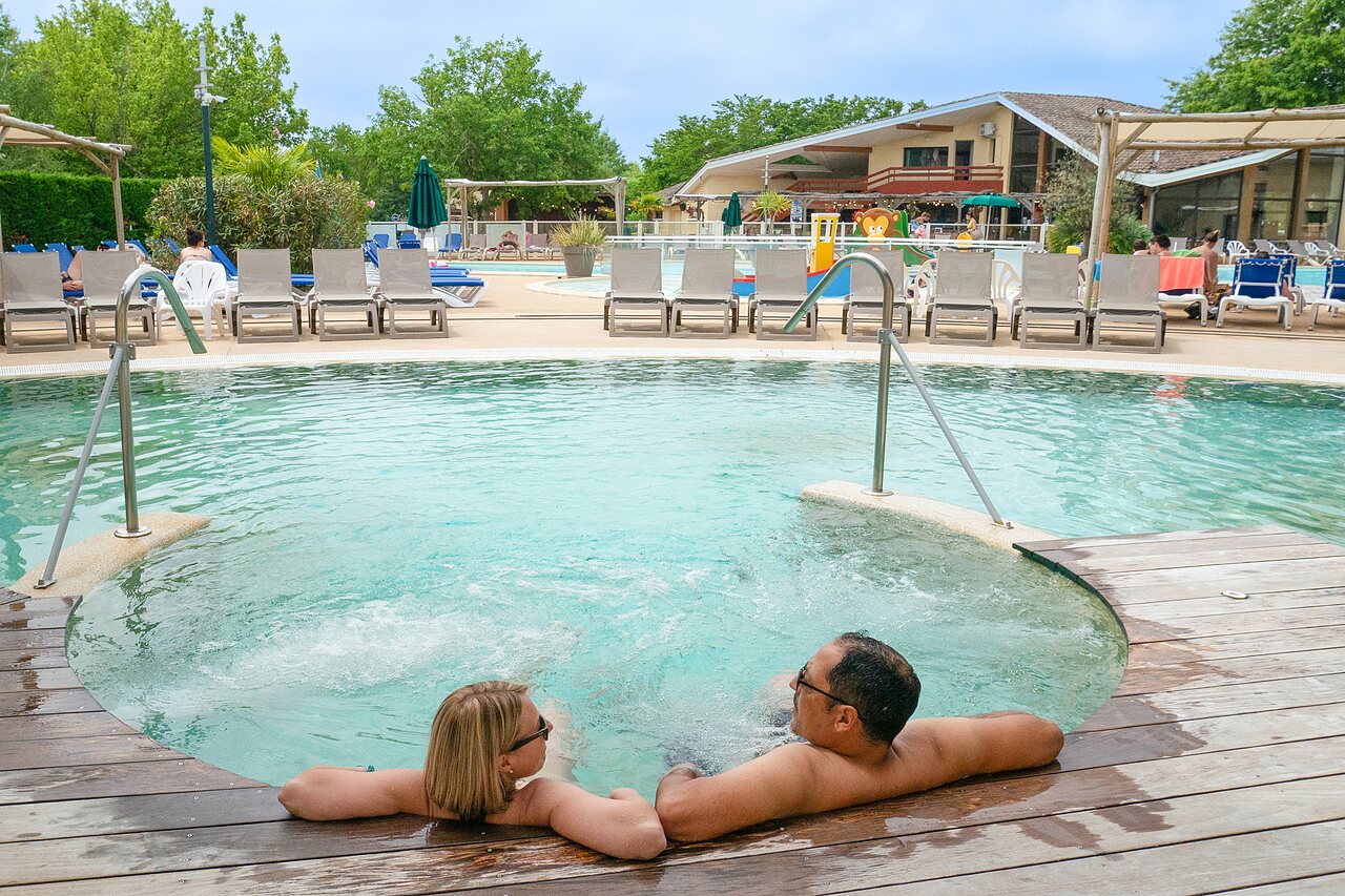 Couple enjoying outdoor jacuzzi at CLICOCHIC Bimbo campsite in BISCARROSSE (40).