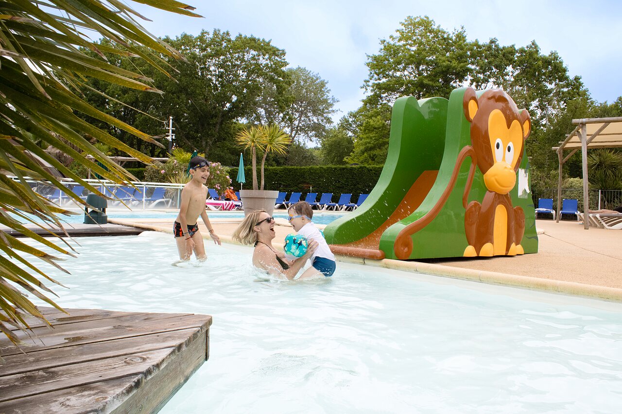 Family in swimming pool with monkey slide at CLICOCHIC Bimbo campsite in BISCARROSSE (40).