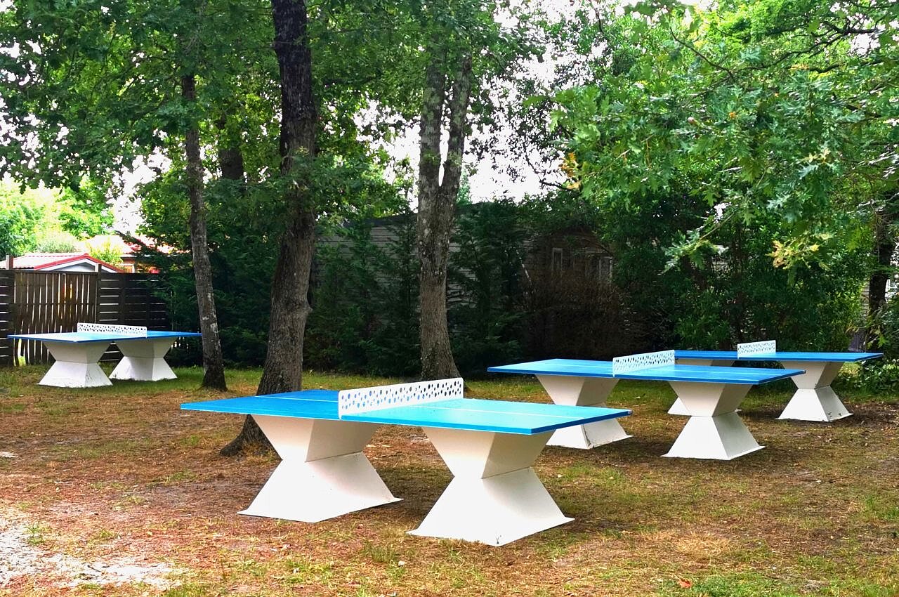 Blue outdoor ping-pong tables under trees at CLICOCHIC Bimbo campsite in BISCARROSSE (40).