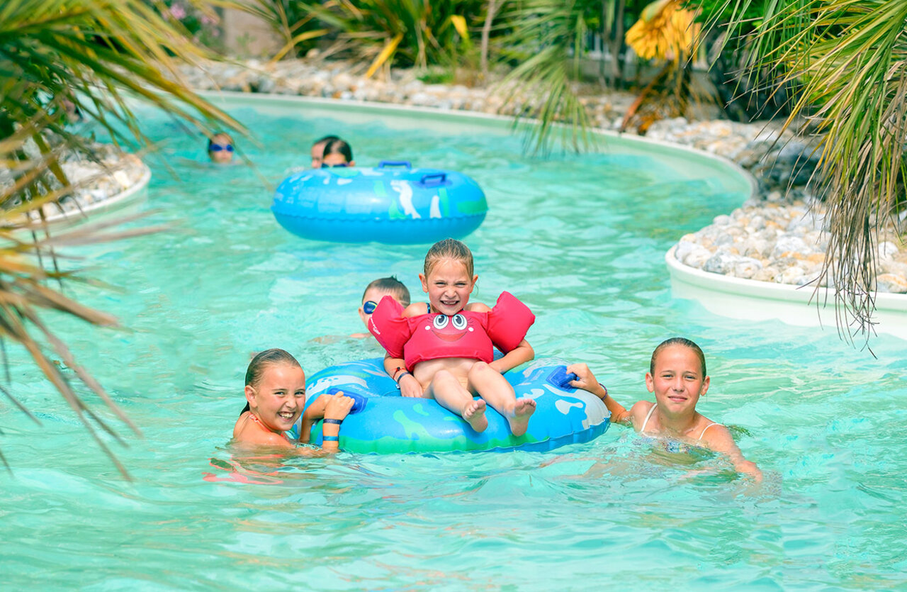 Smiling children on floats in lazy river pool VAGUES OCEANES Bois Joly.