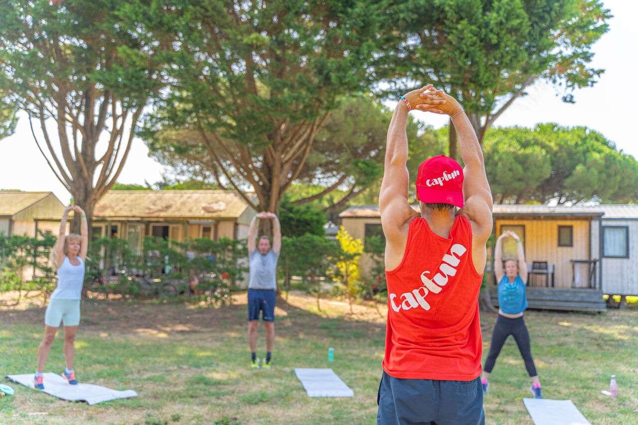 Outdoor stretching class with Capfun animator at CAPFUN Bonne Etoile campsite in BOIS PLAGE EN RE (17).