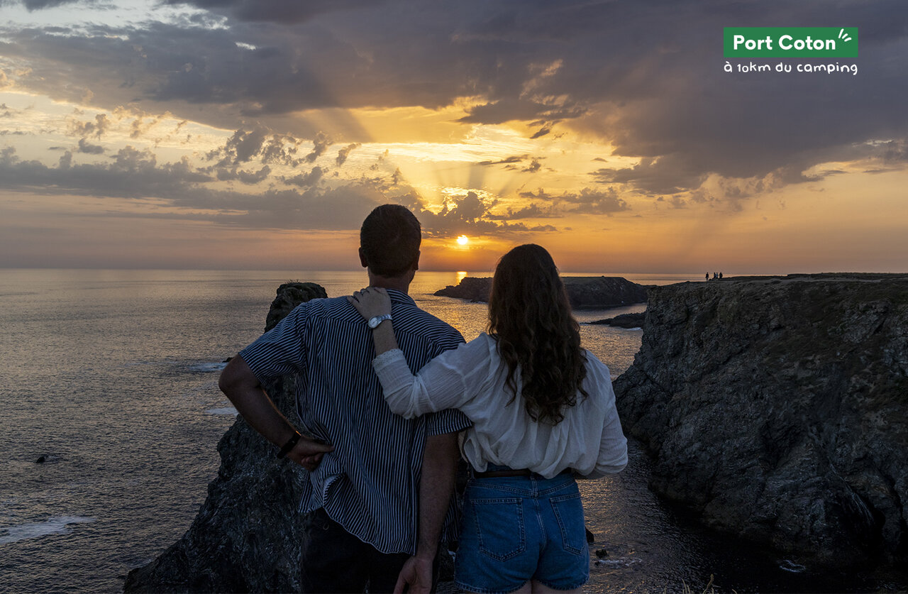 Couple admiring sunset over Port Coton cliffs, Belle-�le-en-Mer island.