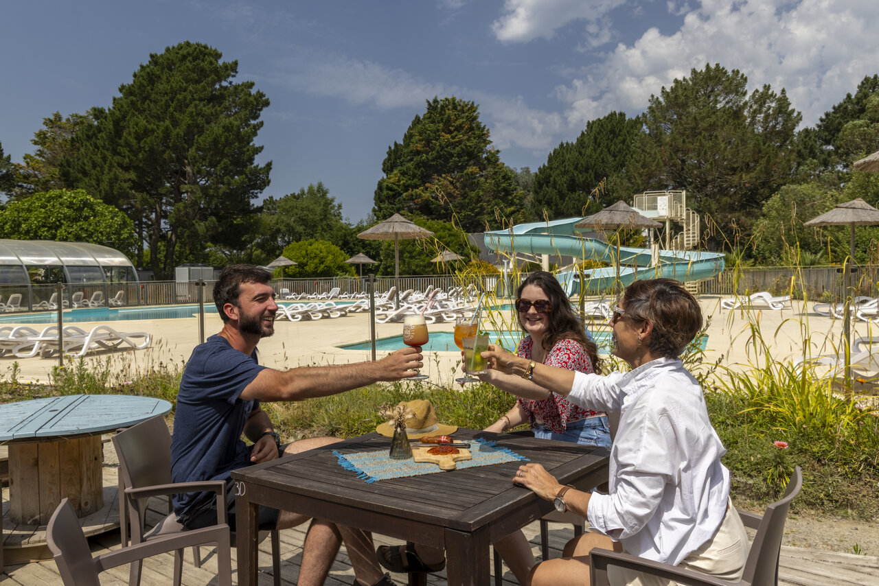 Guests toasting at the bar, outdoor pool and waterslide at camping CLICOCHIC Bord�n�o Belle-�le-en-Mer in Le Palais (56).