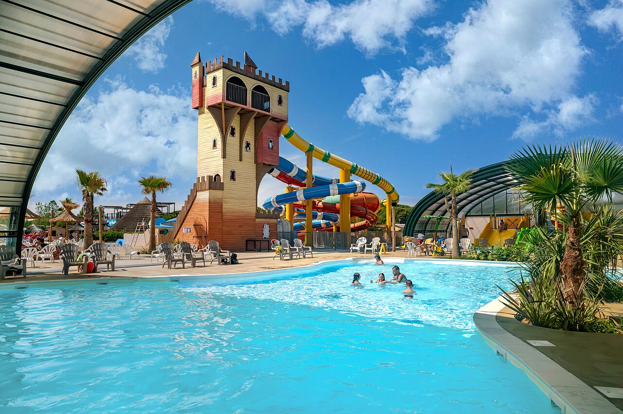 Outdoor pool with giant waterslides and castle structure at CAPFUN Boucanet campsite in LE GRAU DU ROI (30).