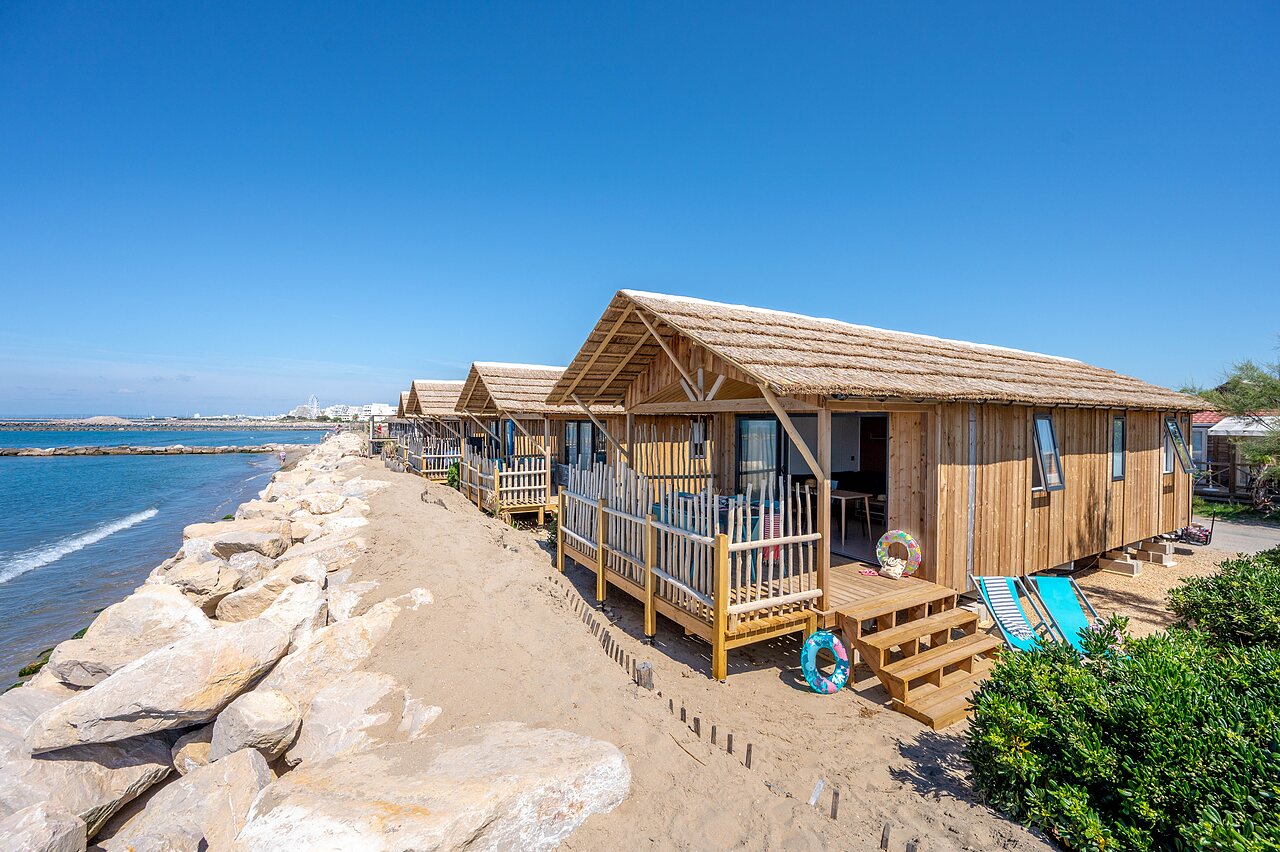 Wooden chalets with thatched roofs on the beach at CAPFUN Boucanet campsite in LE GRAU DU ROI (30).