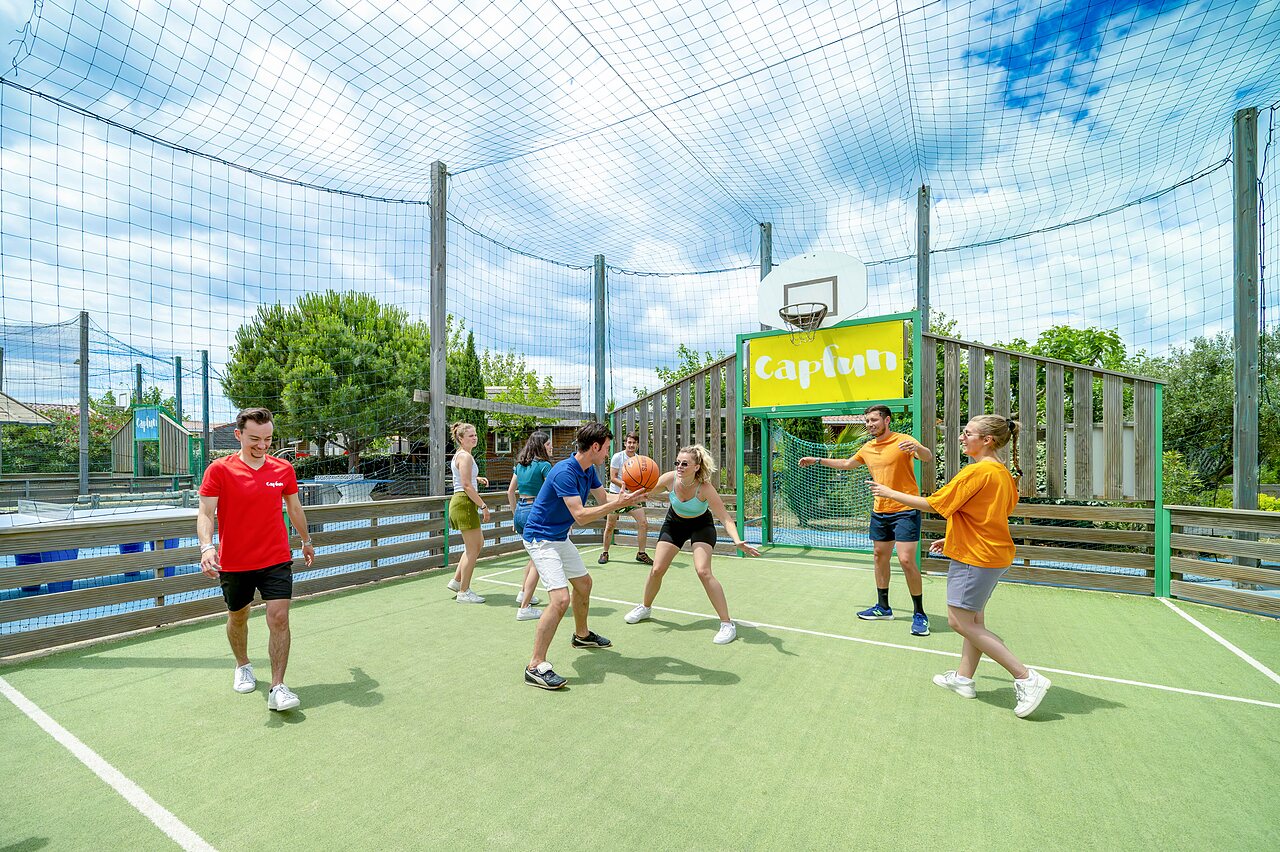 Young people playing basketball on multisport court at CAPFUN Boucanet campsite in LE GRAU DU ROI (30).