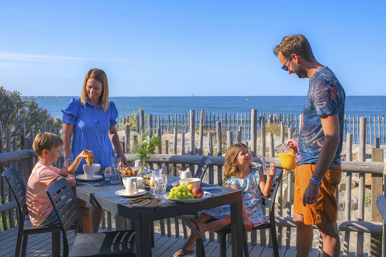 Family having breakfast on terrace with sea view, CAPFUN Boucanet campsite, LE GRAU DU ROI (30).