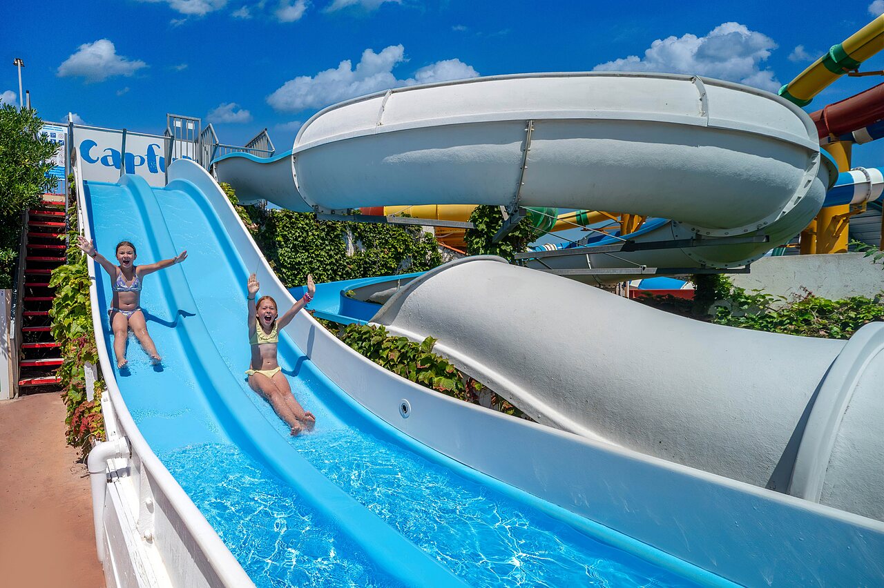 Happy children on blue water slide at CAPFUN Boucanet campsite in LE GRAU DU ROI (30).