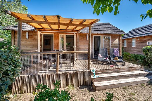 Wooden mobile home with terrace and chairs at CAPFUN Boucanet campsite.